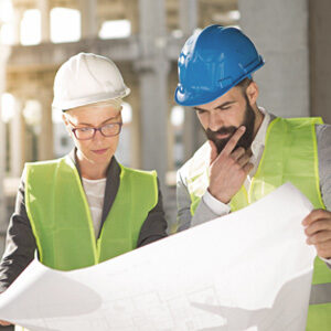 Zwei Architekten mit Bauhelm schauen auf Plan