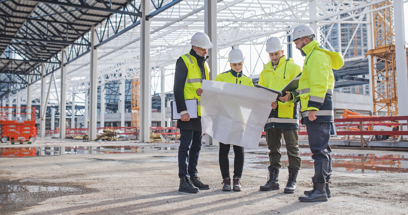 4 Personen schauen auf Baustelle in Plan