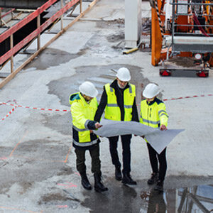 Drei Architekten schauen auf Baustelle in Plan